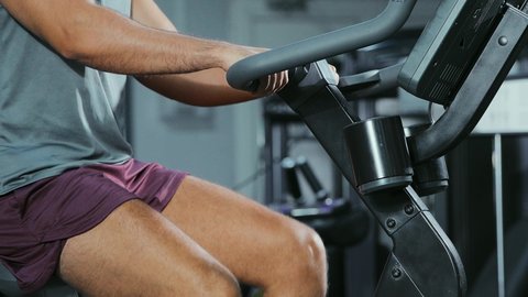 تحسين التنسيق بين الرجلين, استخدام العجلة الهوائية، المحافظة على نظام الحياة الصحي، انشطة ورياضات لتقوية العضلات و الاعصاب، لقطة مقربة رجل عربي خليجي سعودي يرتدي الملابس الرياضية يتمرن في النادي الرياضي