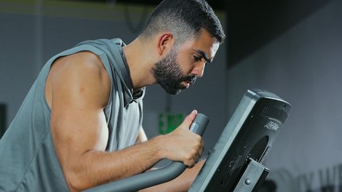 A stationary exercise bike, maintaining a healthy lifestyle, the concept of fitness and agility, activities and sports to strengthen muscles and nerves, an Arab Gulf Saudi man wearing sportswear exercising on a stationary bike