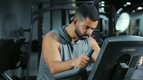 رفع معدل الحرق, قضاء وقت ممتع على العجلة الهوائية، المحافظة على نظام الحياة الصحي، انشطة ورياضات لتقوية العضلات و الاعصاب، رجل عربي خليجي سعودي يرتدي الملابس الرياضية يتمرن في النادي الرياضي
