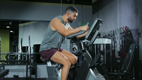 تحسين اللياقة القلبية و التنفسية, المحافظة على نظام الحياة الصحي، مفهوم الرشاقة والصحة، انشطة ورياضات لتقوية العضلات و الاعصاب، رجل عربي خليجي سعودي يرتدي الملابس الرياضية يتمرن على العجلة الهوائية