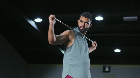 استعادة التوازن بعد التدريب, إطالة العضلات بعد التمرين, نشاط شبابي يساعد على اللياقة البدنية, أهمية الرياضة لبناء جسد قوي، رجل عربي خليجي سعودي يرتدي الزي الرياضي يتمرن باستخدام العصا، أسلوب حياة صحي، تعابير القوة والعزم