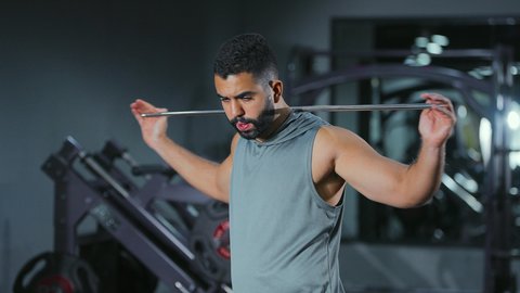 حركة تساعد على تهدئة العضلات, التخفيف من التوتر العضلي, نشاط شبابي يساعد على اللياقة البدنية, أهمية الرياضة لبناء جسد قوي، رجل عربي خليجي سعودي يرتدي الزي الرياضي يتمرن باستخدام العصا، أسلوب حياة صحي، تعابير القوة والعزم