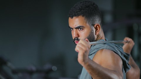 تقليل الشد العضلي, إطالة العضلات بعد التمرين, نشاط شبابي يساعد على اللياقة البدنية, أهمية الرياضة لبناء جسد قوي، رجل عربي خليجي سعودي يرتدي الزي الرياضي يتمرن باستخدام العصا، أسلوب حياة صحي، تعابير القوة والعزم