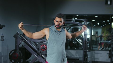 التخفيف من التوتر العضلي, زيادة المرونة وتمديد العضلات، نشاط شبابي يساعد على اللياقة البدنية, أهمية الرياضة لبناء جسد قوي، رجل عربي خليجي سعودي يرتدي الزي الرياضي يتمرن باستخدام العصا، أسلوب حياة صحي، تعابير القوة والعزم