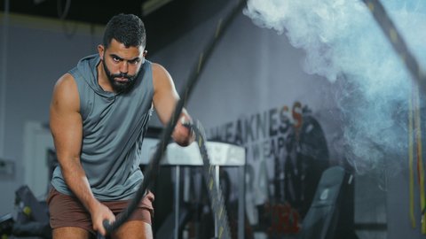 تحكم الجسد في الشد و الإرخاء, المحافظة على توازن الجسم، مفهوم الرشاقة واللياقة البدنية، انشطة ورياضات لتقوية العضلات و الاعصاب، لقطة مقربة لرجل عربي خليجي سعودي يرتدي الملابس الرياضية يقوم بممارسة التمارين بواسطة الحبل الثقيل