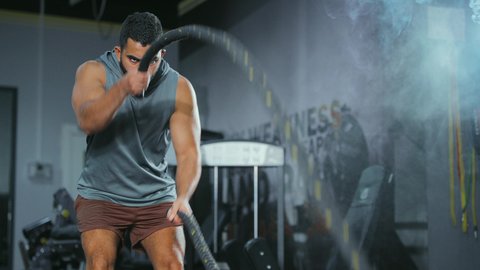Maintaining proper performance, the concept of agility and physical fitness, activities and sports to strengthen muscles and nerves, a close-up shot of a Saudi Arabian Gulf man wearing sportswear exercising with a heavy rope, gestures of strength and determination.