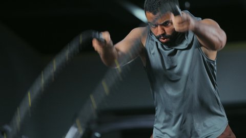 تمرين مكثف لتقوية العضلات, المحافظة على توازن الجسم، مفهوم الرشاقة واللياقة البدنية، رجل عربي خليجي سعودي يرتدي الملابس الرياضية يقوم بممارسة التمارين بواسطة الحبل الثقيل