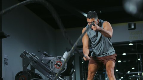 تمرين يعتمد على الجهد المكثف والسريع, المحافظة على توازن الجسم، مفهوم الرشاقة واللياقة البدنية، انشطة ورياضات لتقوية العضلات و الاعصاب، رجل عربي خليجي سعودي يرتدي الملابس الرياضية يقوم بممارسة التمارين بواسطة الحبل الثقيل