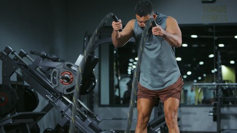 الدمج بين السرعة والسيطرة,  المحافظة على توازن الجسم، مفهوم الرشاقة واللياقة البدنية، انشطة ورياضات لتقوية العضلات و الاعصاب، رجل عربي خليجي سعودي يرتدي الملابس الرياضية يقوم بممارسة التمارين بواسطة الحبل الثقيل