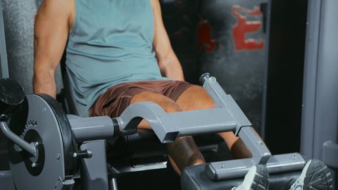 Balanced performance between push and return; a close-up shot of a young Saudi Arabian man in athletic wear exercising on a leg press machine at the gym; attention to health and fitness; use of exercise equipment; a healthy lifestyle.