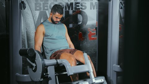 تطوير أداء العضلات السفلية, الاهتمام بالصحة و الرشاقة, استخدام الأجهزة الرياضية، شاب عربي خليجي سعودي يرتدي الزي الرياضي يتمرن على جهاز تمارين الارجل في الجيم، أسلوب حياة صحي، المحافظة على التوازن الجسدي