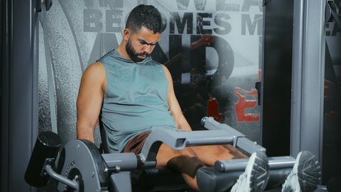 تحسين قدرة الأرجل على التحمل, الاهتمام بالصحة و الرشاقة, استخدام الأجهزة الرياضية، شاب عربي خليجي سعودي يرتدي الزي الرياضي يتمرن في الجيم، أسلوب حياة صحي، المحافظة على التوازن الجسدي