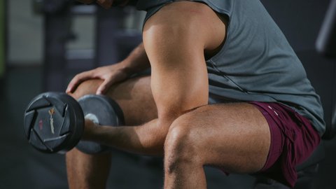 Maintaining a healthy and fit body, using weights, a young Saudi Arabian man wearing sportswear performs weightlifting exercises, strengthening nerves and muscles, a healthy lifestyle, a youthful activity that helps with physical fitness, bodybuilding
