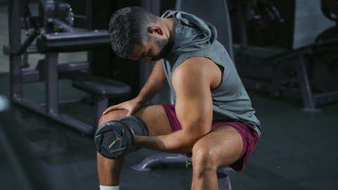 التمرين باستخدام الدمبل، استخدام الاثقال الرياضية، شاب عربي خليجي سعودي يرتدي الزي الرياضي يقوم بممارسة تمارين رفع الأوزان، تقوية الأعصاب والعضلات، أسلوب حياة صحي، نشاط شبابي يساعد على اللياقة البدنية, رياضة كمال الأجسام