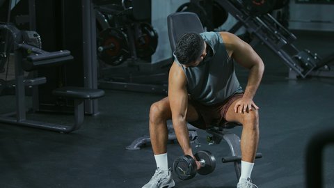 استخدام الاثقال الرياضية، شاب عربي خليجي سعودي يرتدي الزي الرياضي يقوم بممارسة تمارين رفع الأوزان، تقوية الأعصاب والعضلات، أسلوب حياة صحي، نشاط شبابي يساعد على اللياقة البدنية, رياضة كمال الأجسام