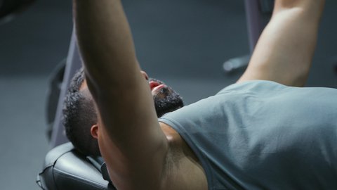 التدرب بجد وعزيمة, إيماءات القوة والثقة, الاهتمام بالصحة واللياقة الجسدية، رياضة كمال الأجسام، استخدام الاثقال الرياضية، شاب عربي خليجي سعودي يرتدي الزي الرياضي يقوم بممارسة تمارين رفع الأوزان، تقوية الأعصاب والعضلات