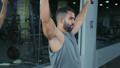 نمط حياة صحي ومفيد، حرق الدهون وتقليل الوزن، نشاط لتقوية العضلات، الاهتمام بالصحة و الرشاقة, استخدام الأجهزة الرياضية، شاب عربي خليجي سعودي يرتدي الزي الرياضي يقوم بممارسة تمارين الظهر على آلة السحب العلوي