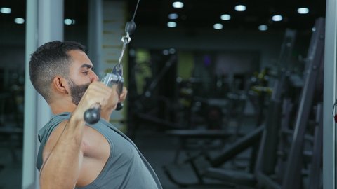 مفهوم اللياقة والرشاقة، نمط حياة صحي ومفيد، حرق الدهون وتقليل الوزن، نشاط لتقوية العضلات، استخدام الأجهزة الرياضية، شاب عربي خليجي سعودي يرتدي الزي الرياضي يقوم بممارسة تمارين الظهر على آلة السحب العلوي