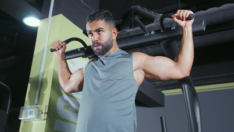 التوازن و التحكم العضلي,  تقوية الأعصاب والعضلات، أسلوب حياة صحي، نشاط شبابي يساعد على اللياقة البدنية, استخدام الأجهزة الرياضية، شاب عربي خليجي سعودي يرتدي الزي الرياضي يقوم بممارسة تمرين تقوية عضلات الصدر و الذراعين و الكتفين على جهاز المتوازي