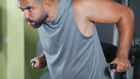 أسلوب حياة صحي، نشاط شبابي يساعد على اللياقة البدنية, تمارين كمال الأجسام، استخدام الأجهزة الرياضية، شاب عربي خليجي سعودي يرتدي الزي الرياضي يقوم بممارسة تمرين تقوية عضلات الصدر و الذراعين و الكتفين على جهاز المتوازي