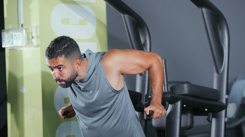 تقوية الأعصاب والعضلات، أسلوب حياة صحي، نشاط شبابي يساعد على اللياقة البدنية, استخدام الأجهزة الرياضية، شاب عربي خليجي سعودي يرتدي الزي الرياضي يقوم بممارسة تمرين تقوية عضلات الصدر و الذراعين و الكتفين على جهاز المتوازي