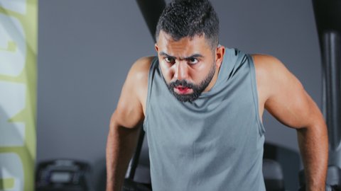 استخدام الأجهزة الرياضية، شاب عربي خليجي سعودي يرتدي الزي الرياضي يقوم بممارسة تمرين تقوية عضلات الصدر و الذراعين و الكتفين على جهاز المتوازي, تقوية الأعصاب والعضلات، أسلوب حياة صحي، نشاط شبابي يساعد على اللياقة البدنية