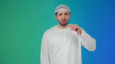 مفهوم الكسل والخمول، تعابير النعاس والحاجه الى النوم، بورتريه لرجل عربي خليجي اماراتي يرتدي الكندورة والطاقية يفرك عينيه بإيماءات النعاس, الإحساس بالتعب والتثاؤب , خلفيه ملونة