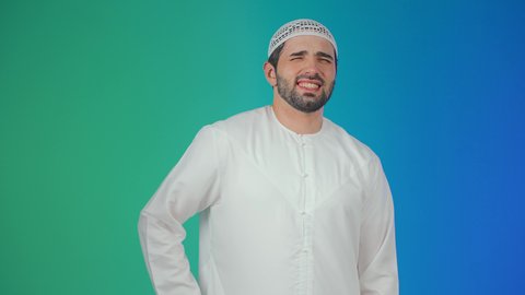 الأوجاع والآلام العصبية، طلب المساعده والحاجه للعلاج، التهاب العضلات والمفاصل، بورتريه لشاب عربي خليجي اماراتي يرتدي الكندورة والقبعة البيضاء يضع يده على ظهره بايماءات الألم والتعب والأرهاق، خلفية ملونة.