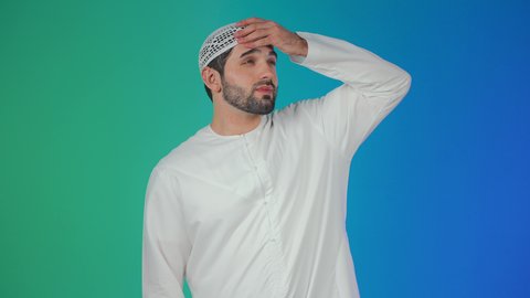 أعراض الاصابة بالحمى والتعب الجسدي وقياس درجه حراره الجسم، بورتريه لرجل عربي خليجي اماراتي يرتدي الكندورة والقبعة البيضاء يقوم بوضع يده على راسه بتعابير قياس الحرارة، مفهوم الاهتمام بالصحة والحاجه الى العلاج, خلفية ملونة
