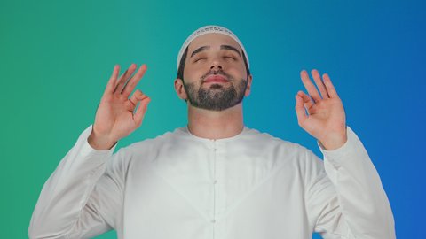 القبول والموافقة والرضا،  علامة الجودة والامتياز، بورتريه لرجل عربي خليجي اماراتي يرتدي الكندورة والطاقيه يشير بيده بإيماءات وتعابير وجه و يدين تدل على الاعجاب، التعبير عن الجودة والاتقان، خلفية ملونة