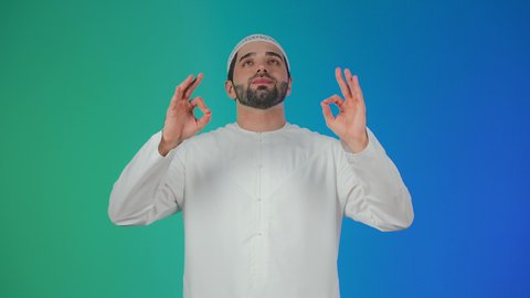 علامة الجودة والامتياز، بورتريه لرجل عربي خليجي اماراتي يرتدي الكندورة والطاقيه يشير بيده بإيماءات وتعابير وجه و يدين تدل على الاعجاب، التعبير عن الجودة والاتقان، القبول والموافقة والرضا، خلفية ملونة