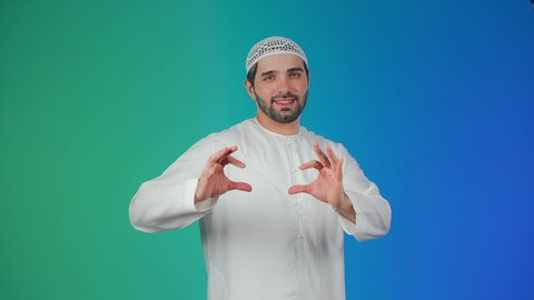 Expressions of joy, happiness, and delight, showing feelings of love and passion, the concept of affection and tenderness, a portrait of a young Arab Gulf Emirati man wearing a kandura and a headscarf, raising his hands in gestures shaped like a heart, with a colorful background.