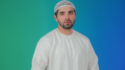 حماية النفس من ضرر خارجي, طلب التوقف والإمتناع عن فعل شيء ما، الرعب والذعر والرهبة من شيء ما،  بورتريه لرجل عربي خليجي اماراتي يرتدي الكندورة والطاقية ويرفع كفيه لأعلى بإيماءات الخوف، خلفية ملونة