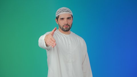 The concept of peace and welcome, different facial expressions and body language, a portrait of an Emirati Arab man wearing a kandura and a headscarf raising his left hand to greet, gestures indicating happiness, colorful background.