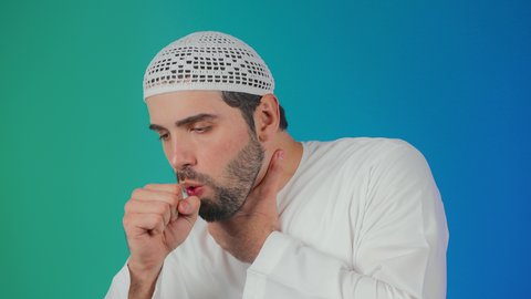 الكحة والتهاب الحلق والحاجة للعلاج، الإصابة بالأنفلونزا ونزلات البرد, إيماءات الإرهاق والتعب الشديد، بورتريه لرجل عربي خليجي اماراتي يرتدي الكندورة والطاقية يضع يده أمام فمه ويقوم بالسعال, خلفية ملونه