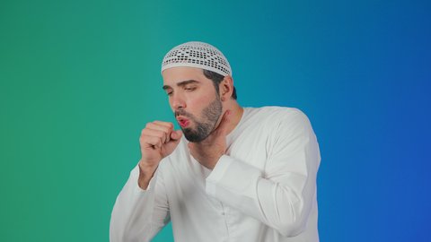إيماءات الإرهاق والتعب الشديد، الإصابة بالأنفلونزا ونزلات البرد, الكحة والتهاب الحلق والحاجة للعلاج، بورتريه لرجل عربي خليجي اماراتي يرتدي الكندورة والطاقية يضع يده أمام فمه ويقوم بالسعال, خلفية ملونه