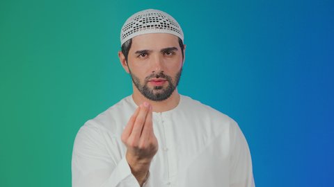 التهديد و التوعد لشيء ما، بورتريه لرجل عربي خليجي اماراتي يرتدي الكندورة والطاقية ينظر الى الكاميرا يرفع يده نحو الأعلى بإيماءات طلب الإنتظار, مفهوم الصبر والتريث و التأني, خلفية ملونة
