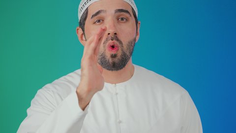 Calling out loudly, placing the hand next to the mouth to amplify the sounds, a portrait of a young Emirati Gulf Arab man wearing a kandura and a headscarf looking at the camera with gestures calling someone, shouting and speaking in a loud tone to be heard well, conversations and social communication, colorful background.