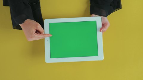 استعمال جهاز تقني حديث لتصفح الصور والفيديوهات بسهولة، استخدام التكنولوجيا في الترفيه، عرض شاشة كروما خضراء فارغة, تصوير علوي عامودي ليد امرأة عربية خليجية سعودية ترتدي العباءة السوداء تستخدم التابلت,  تصفح مواقع و وسائل التواصل الاجتماعي