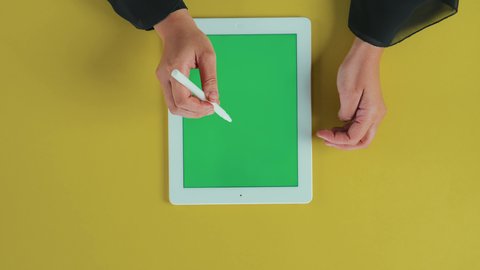 ايماءات النقر على الشاشة، مفهوم الترفيه بالتقنية والتكنولوجيا الحديثة، التسلية والاستمتاع بالاستراحة، تصوير علوي عامودي ليد امرأة عربية خليجية سعودية تقوم باستخدام الجهاز اللوحي , عرض شاشة خضراء كروما فارغة