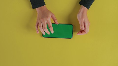 اللعب على الهاتف المحمول، قضاء وقت ممتع على الإنترنت، استخدام الأجهزة التقنية الحديثة، تصوير علوي عامودي ليد امرأة عربية خليجية سعودية ترتدي العباءة السوداء و تستخدم الموبايل, متابعة الافلام والمسلسلات عبر الجوال، تصفح أخبار مواقع التواصل الاجتماعي, عرض شاشة خضراء فارغة, كروما