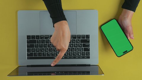 مراجعة البريد الالكتروني, متابعة مواقع التواصل الاجتماعي، عقد الاجتماعات عبر الانترنت، تصوير علوي عامودي ليد امرأة عربية خليجية سعودية ترتدي العباءة السوداء تستخدم اللابتوب و تحمل هاتف محمول بشاشة خضراء فارغة, كروما