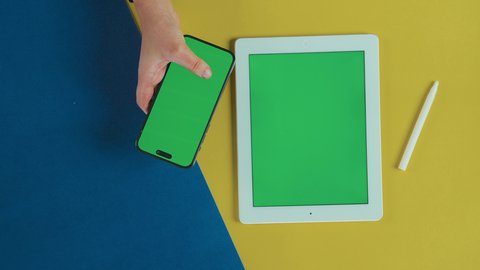 التأكد من شئ ما عبر الهاتف, عرض شاشة خضراء فارغة على الأجهزة التقنية، استخدام التكنولوجيا الحديثة في انجاز المهام عن بعد، تصوير علوي عامودي ليد امرأة عربية خليجية سعودية ترتدي العباءة السوداء تستخدم تابلت و جوال, كروما