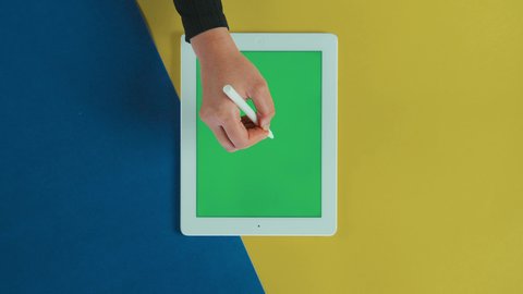 مفهوم التصحيح الالكتروني, تصوير علوي عامودي ليد امرأة عربية خليجية سعودية ترتدي العباءة السوداء تستخدم تابلت بشاشة خضراء فارغة و تقوم برسم اشارة الصح على الجهاز اللوحي, استخدام التكنولوجيا و التقنيات الحديثة، كروما