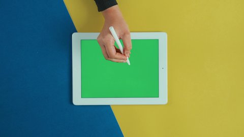 سهولة التحكم في التفاصيل, استخدام التكنولوجيا و التقنيات الحديثة، مفهوم إدارة المشاريع وانجاز المهام عن بعد، تصوير علوي عامودي ليد امرأة عربية خليجية سعودية ترتدي العباءة السوداء تستخدم جهاز تابلت بشاشة خضراء فارغة مع القلم الخاص به، تصفح مواقع و وسائل التواصل الاجتماعي, كروما