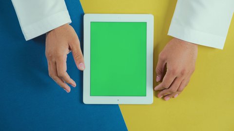 استعمال خاصية تكبير الصور, استخدام التكنولوجيا و التقنيات الحديثة، مفهوم إدارة المشاريع وانجاز المهام عن بعد، تصوير علوي عامودي ليد رجل عربي سعودي خليجي يرتدي الثوب التقليدي و يستخدم جهاز التابلت، تصفح مواقع و وسائل التواصل الاجتماعي, كروما