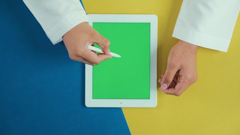 رسم الصور و التصاميم, استخدام التكنولوجيا و التقنيات الحديثة، مفهوم إدارة المشاريع وانجاز المهام عن بعد، تصوير علوي عامودي ليد رجل عربي سعودي خليجي يرتدي الثوب التقليدي و يستخدم جهاز تابلت بشاشة خضراء فارغة، تصفح مواقع و وسائل التواصل الاجتماعي, كروما