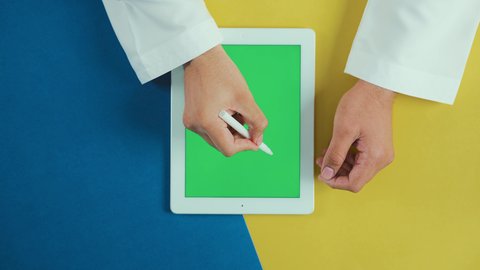 تسهيل عملية التدوين, استخدام التكنولوجيا و التقنيات الحديثة، مفهوم إدارة المشاريع وانجاز المهام عن بعد، تصوير علوي عامودي ليد رجل عربي سعودي خليجي يرتدي الثوب التقليدي و يستخدم جهاز تابلت بشاشة خضراء فارغة مع القلم الخاص به، تصفح مواقع و وسائل التواصل الاجتماعي, كروما