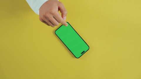 تطبيقات وخدمات الهاتف المحمول، التقدم التكنولوجي والتطور التقني، تصفح مواقع التواصل الاجتماعي، عرض شاشة خضراء فارغة على الأجهزة التقنية، استخدام التكنولوجيا الحديثة لإنجاز المهام عن بُعد، لقطة عمودية من الأعلى ليد رجل خليجي سعودي يرتدي الثوب التقليدي و يستخدم الجوال, كروما