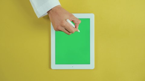 الرسم على الجهاز اللوحي, استخدام التكنولوجيا و التقنيات الحديثة، مفهوم إدارة المشاريع وانجاز المهام عن بعد، تصوير علوي عامودي ليد رجل عربي سعودي خليجي يرتدي الثوب التقليدي و يستخدم جهاز تابلت بشاشة خضراء فارغة، تصفح مواقع و وسائل التواصل الاجتماعي, كروما